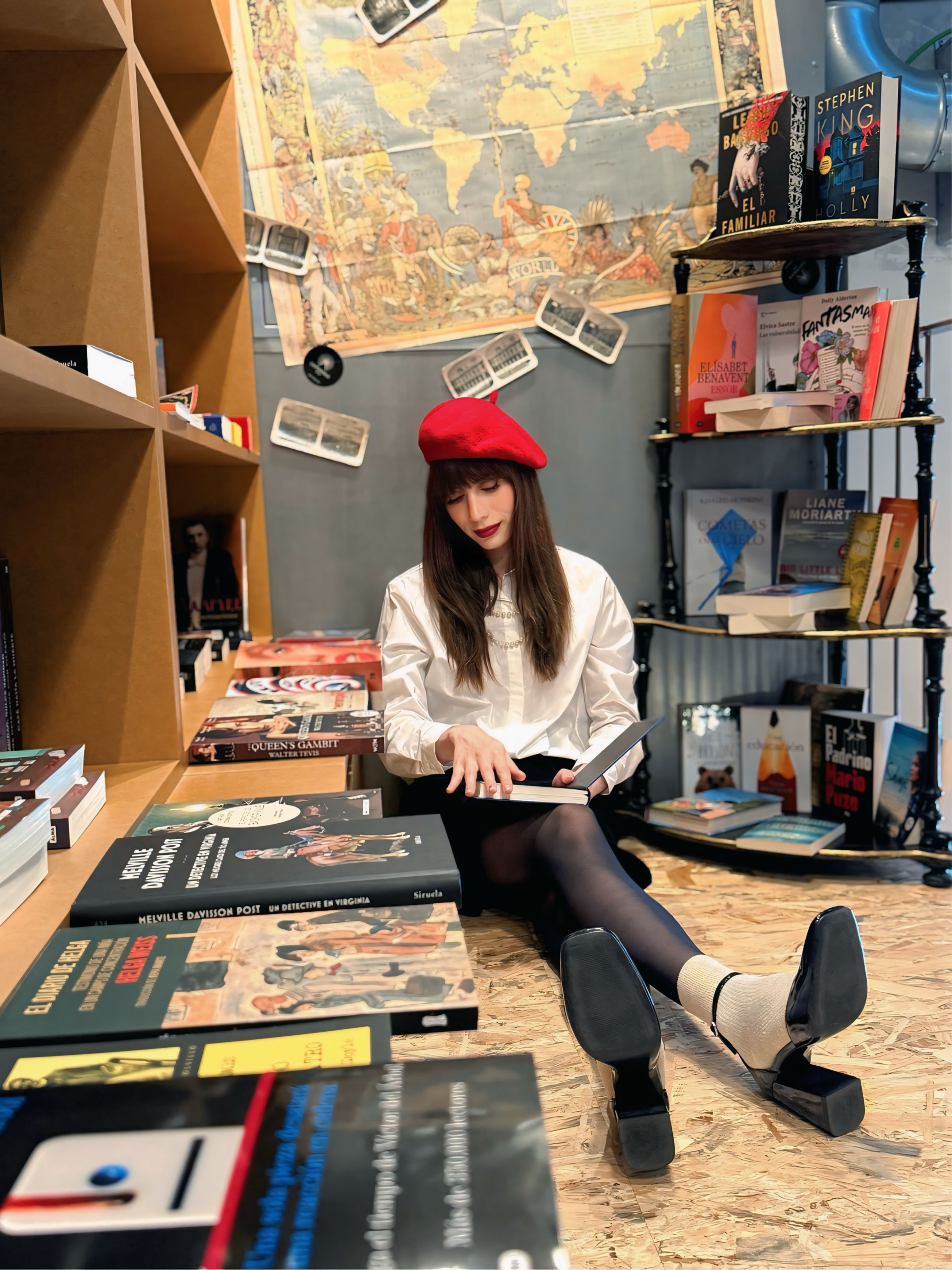 María en librería con boina roja leyendo entre libros