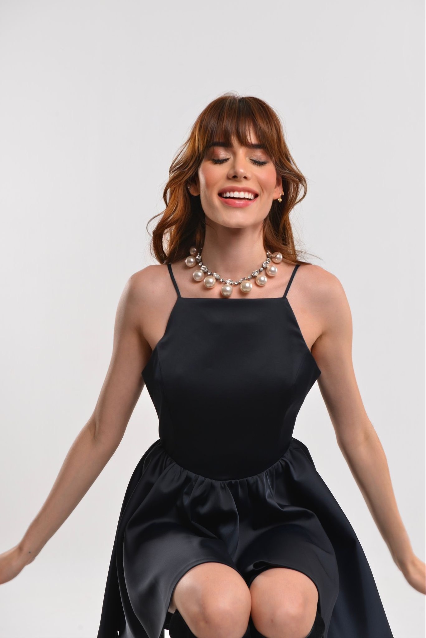 Retrato profesional con vestido negro y collar de perlas